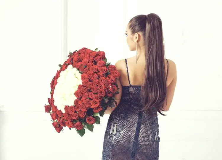Arkası dönük duran, saçları at kuyruğu şeklinde toplanmış olan genç kadının üzerinde siyah ve askılı bir elbise bulunuyor. Genç kadın elinde kırmızı ve beyaz güllerin bulunduğu büyük bir demet tutuyor.
